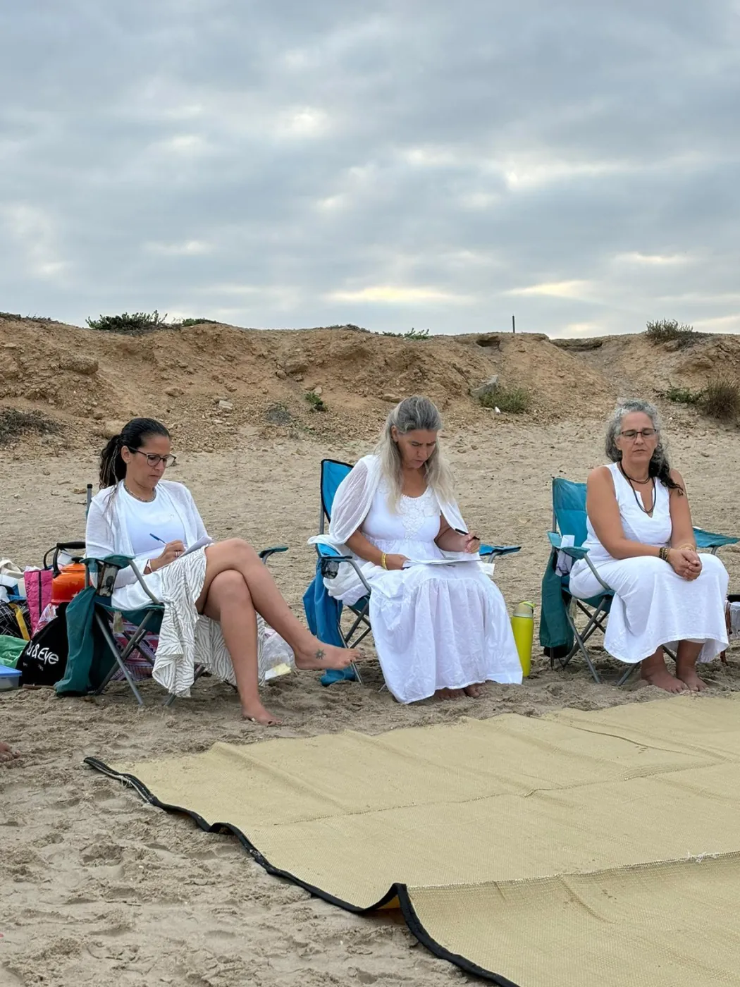 נשים בלבן בטקס כתיבה ומדיטציה על חוף הים